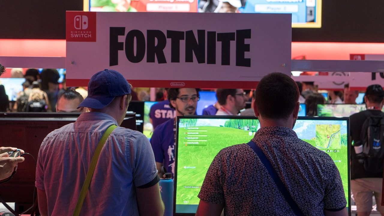 Visitors playing Fortnite at rows of gaming stations at E3 2018